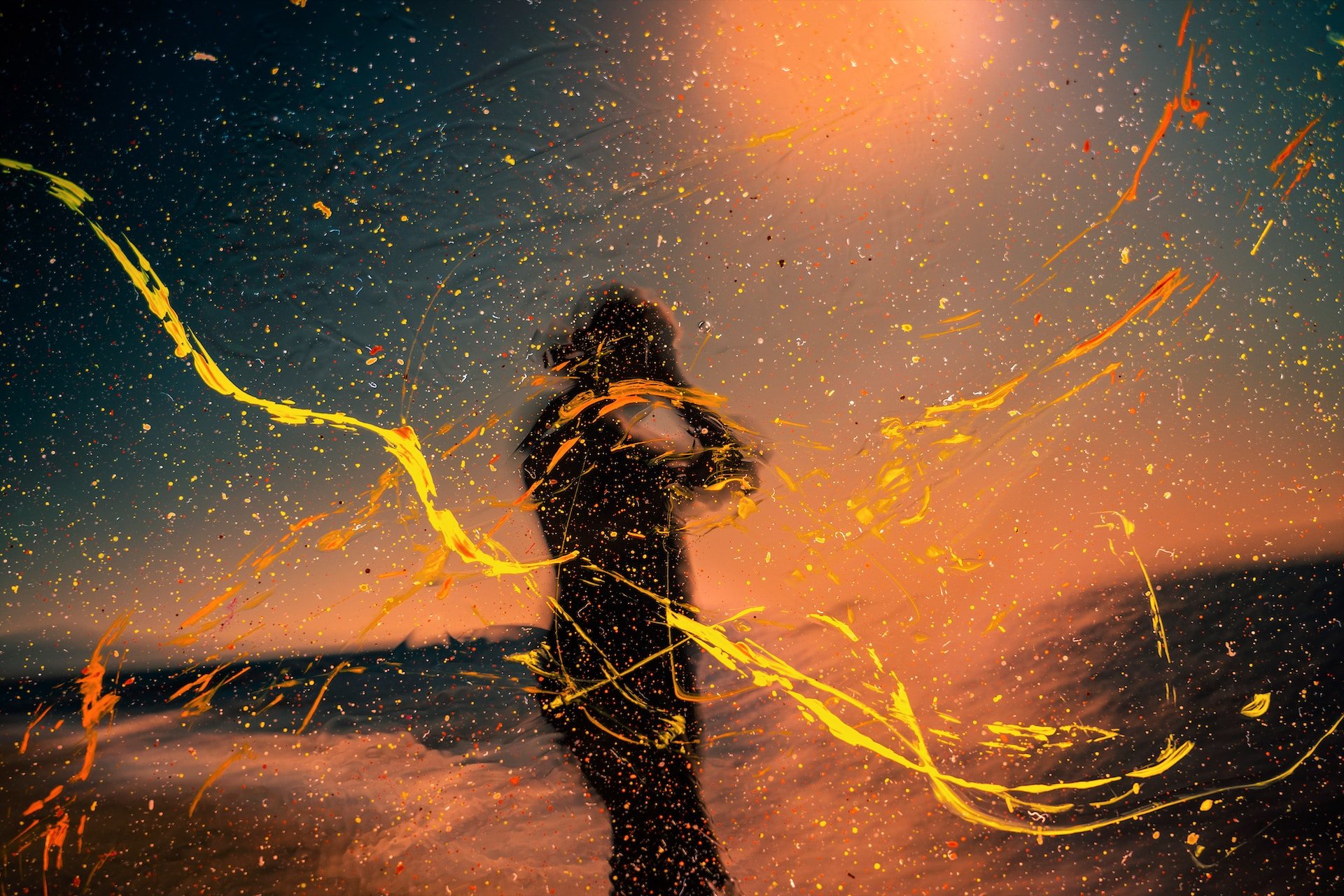 Orange and yellow abstract art over silhouette of woman hands to head